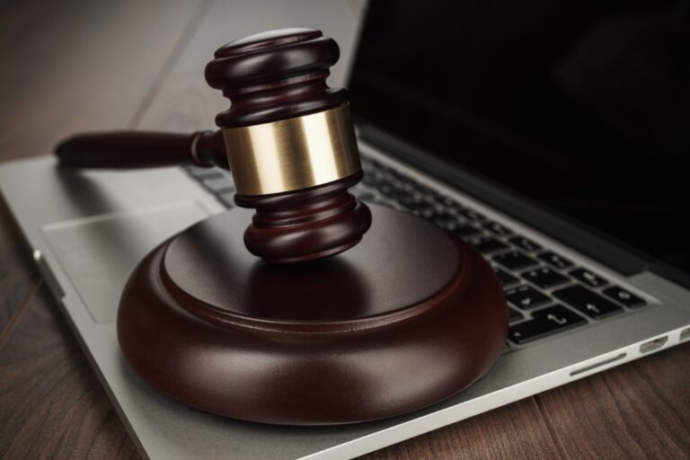 A wooden judge's gavel rests on a laptop keyboard, symbolizing the intersection of law and technology, often navigated with the help of a bankruptcy lawyer near me for chapter 7 or chapter 13 bankruptcy cases.